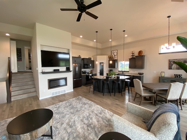 1819 67th Ave S, Fargo, ND 58104 - living room with light wood-style flooring, recessed lighting, a ceiling fan, stairs, and a glass covered fireplace