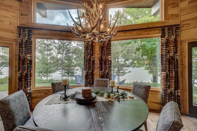 16267 Conners Ln, Sand Lake Twp, WI 54876 - dining room with a chandelier, wooden walls, wood finished floors, plenty of natural light, and a water view