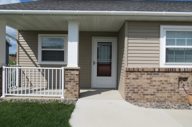 307 14th St N, Cold Spring, MN 56320 - property entrance with brick siding, a porch, and a shingled roof