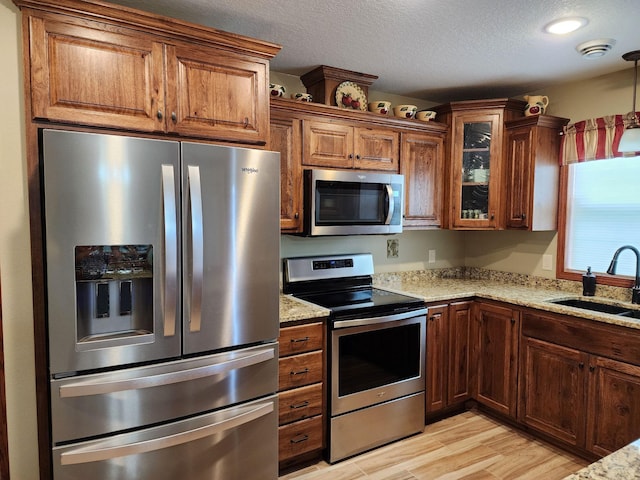 307 14th St N, Cold Spring, MN 56320 - kitchen with stainless steel appliances, light stone countertops, light wood-style flooring, glass insert cabinets, and a textured ceiling