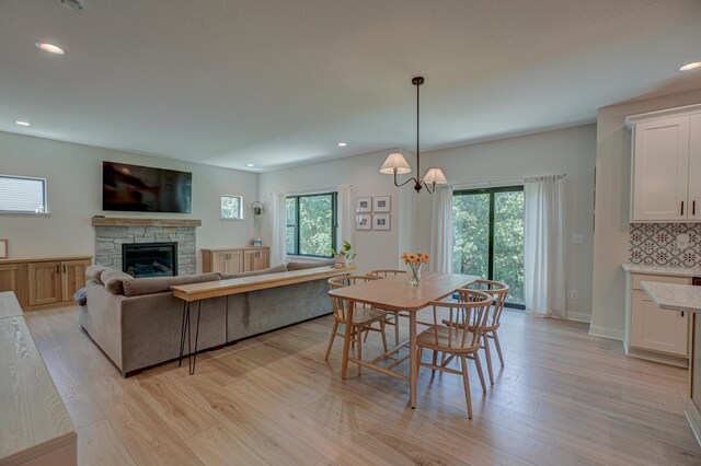 21 Windsor Wood Path, Hudson, WI 54016 - dining space featuring light wood-type flooring, a stone fireplace, a chandelier, and recessed lighting