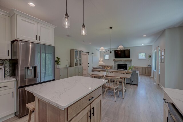 21 Windsor Wood Path, Hudson, WI 54016 - kitchen with stainless steel fridge with ice dispenser, a barn door, open floor plan, light wood-style flooring, and recessed lighting