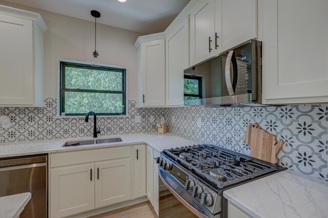 21 Windsor Wood Path, Hudson, WI 54016 - kitchen with stainless steel appliances, white cabinetry, light stone counters, backsplash, and hanging light fixtures