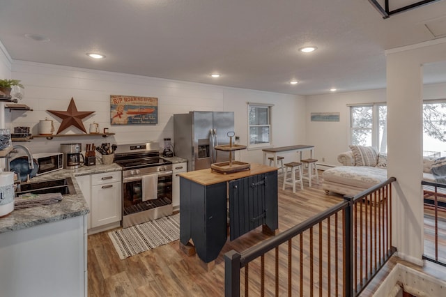 36722 Birch Dr, Jenkins Twp, MN 56474 - kitchen with appliances with stainless steel finishes, light wood-style flooring, butcher block counters, white cabinets, and recessed lighting