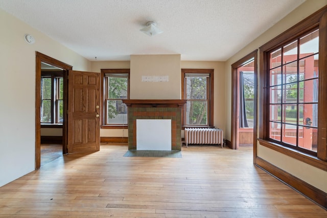 211 Saint Marie St, Duluth, MN 55803 - unfurnished living room featuring radiator, a textured ceiling, light wood finished floors, and a fireplace