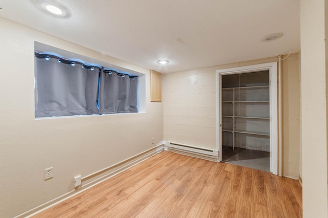 211 Saint Marie St, Duluth, MN 55803 - unfurnished bedroom with a baseboard radiator, light wood-type flooring, a spacious closet, and a closet