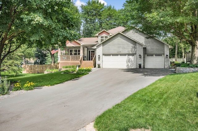 12145 Jonquil St NW, Coon Rapids, MN 55433 - view of front facade with driveway, brick siding, an attached garage, and a porch