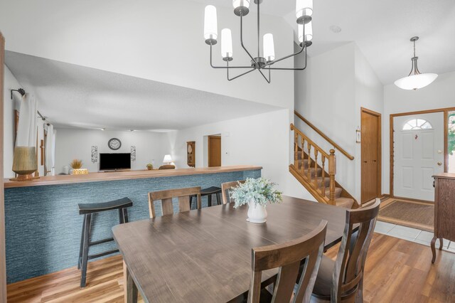 12145 Jonquil St NW, Coon Rapids, MN 55433 - dining area featuring stairway, light wood finished floors, a high ceiling, and a chandelier