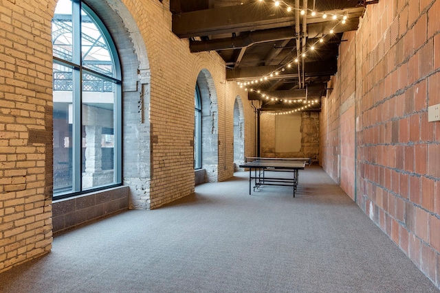 404 Washington Ave N Unit 304, Minneapolis, MN 55401 - hallway with brick wall, carpet flooring, a high ceiling, and a chandelier