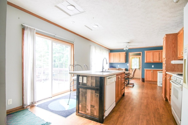 23829 Bulrush Dr, Lake Edward Twp, MN 56465 - kitchen featuring white appliances, a center island with sink, wood finished floors, ornamental molding, and light countertops