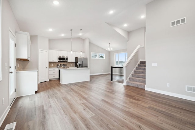 17006 Traprock St NW, Ramsey, MN 55303 - kitchen with stainless steel appliances, open floor plan, vaulted ceiling, white cabinets, and a center island with sink