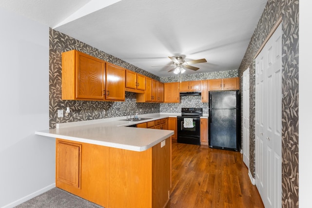 3204 49th St NW, Rochester, MN 55901 - kitchen with black appliances, wallpapered walls, a peninsula, under cabinet range hood, and brown cabinets