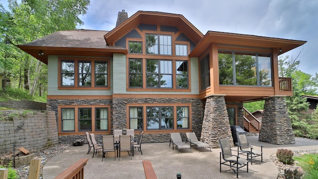 2471 Birch Forest Rd SW, Nisswa, MN 56468 - rear view of property with a patio, stone siding, a chimney, stairway, and a sunroom