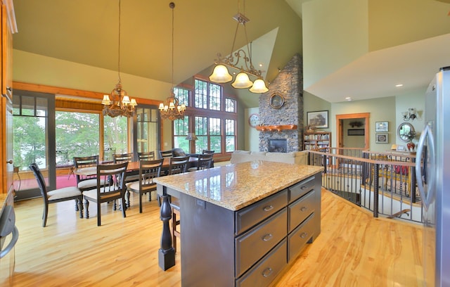 2471 Birch Forest Rd SW, Nisswa, MN 56468 - kitchen with a chandelier, high vaulted ceiling, light wood-type flooring, freestanding refrigerator, and a fireplace