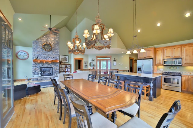 2471 Birch Forest Rd SW, Nisswa, MN 56468 - dining area with high vaulted ceiling, light wood-style flooring, a fireplace, a ceiling fan, and a chandelier