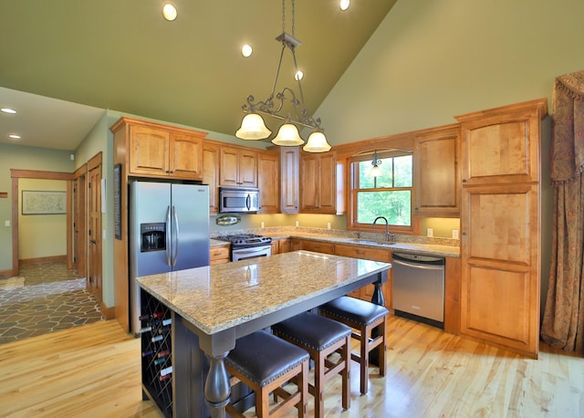 2471 Birch Forest Rd SW, Nisswa, MN 56468 - kitchen with stainless steel appliances, high vaulted ceiling, light wood-style floors, light stone counters, and a center island