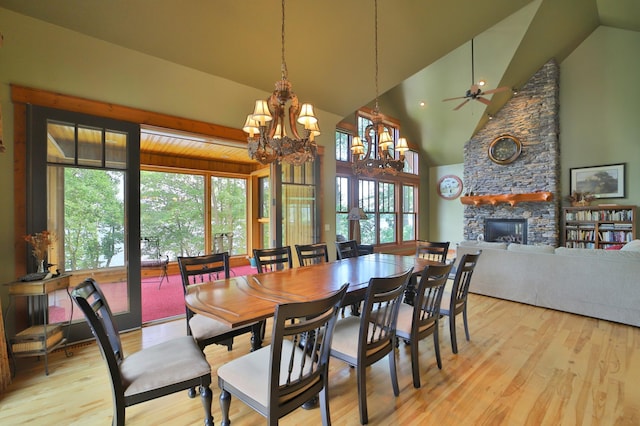 2471 Birch Forest Rd SW, Nisswa, MN 56468 - dining area featuring a chandelier, wood finished floors, a stone fireplace, a ceiling fan, and high vaulted ceiling