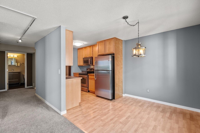48 Groveland Ter Unit B301, Minneapolis, MN 55403 - kitchen featuring stainless steel appliances, a textured ceiling, light wood finished floors, rail lighting, and decorative light fixtures