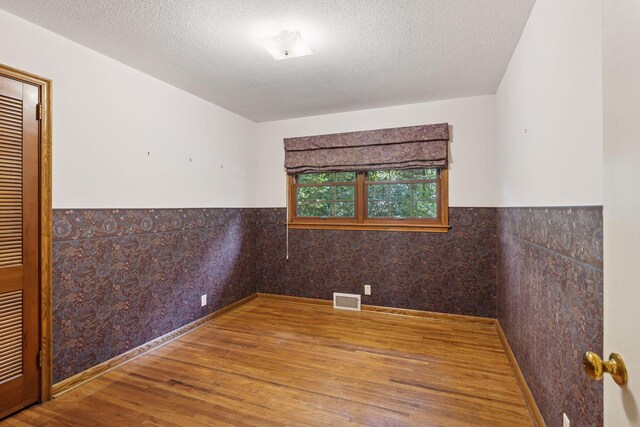 33 Eagle Ridge Rd, North Oaks, MN 55127 - empty room with wood finished floors, a wainscoted wall, and a textured ceiling
