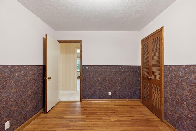 33 Eagle Ridge Rd, North Oaks, MN 55127 - spare room with wood finished floors, a wainscoted wall, and a textured ceiling