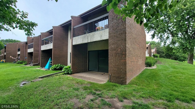 1529 Millpond Ct, Chaska, MN 55318 - rear view of house featuring a balcony, brick siding, and a lawn