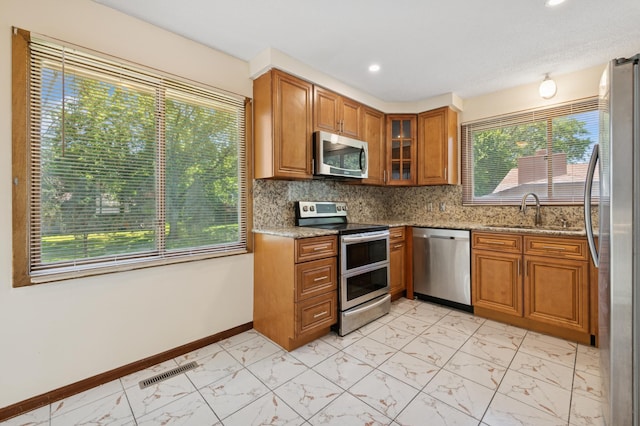 629 73rd Way N, Brooklyn Park, MN 55444 - kitchen with stainless steel appliances, light marble finish flooring, brown cabinetry, light stone counters, and recessed lighting