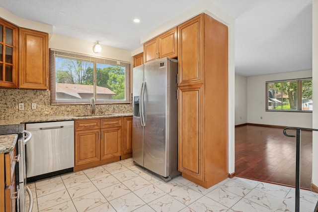 629 73rd Way N, Brooklyn Park, MN 55444 - kitchen with stainless steel appliances, light marble finish flooring, light stone counters, brown cabinetry, and recessed lighting