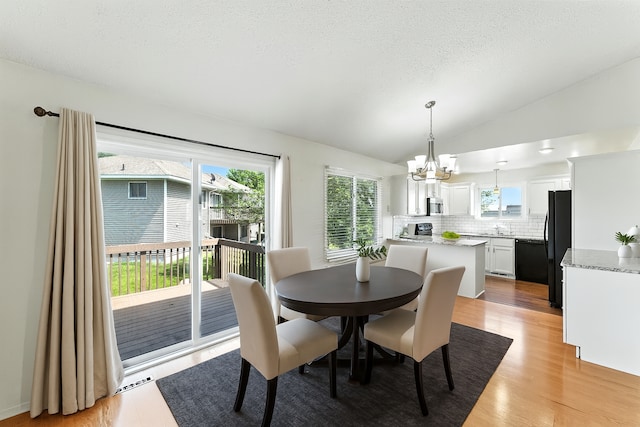 900 Countryside Rd, Waconia, MN 55387 - dining area with a chandelier, healthy amount of natural light, light wood-type flooring, lofted ceiling, and a textured ceiling