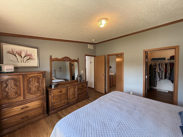 151 Skyline Dr, Granite Falls, MN 56241 - bedroom with dark wood-style floors, a textured ceiling, a spacious closet, ornamental molding, and connected bathroom