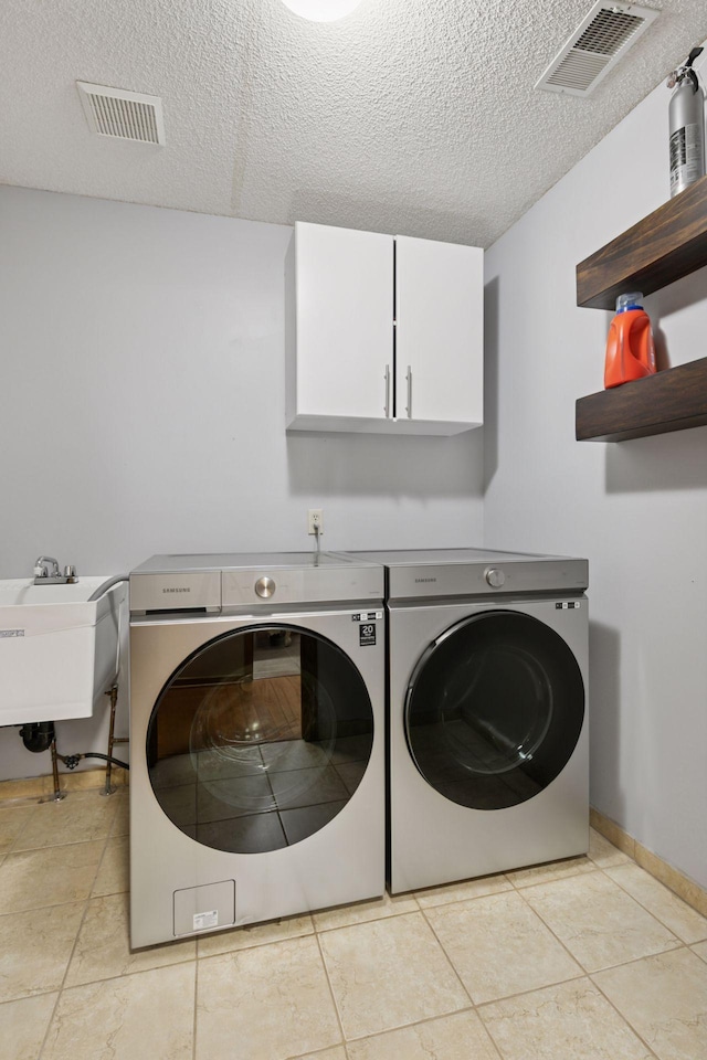 4478 150th St, Savage, MN 55378 - laundry room featuring cabinet space, separate washer and dryer, a textured ceiling, and light tile patterned floors