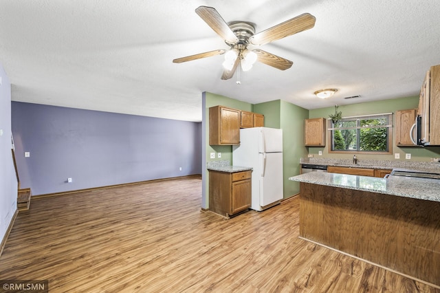 1111 Royal Oaks Dr, Shoreview, MN 55126 - kitchen featuring freestanding refrigerator, light wood-type flooring, a peninsula, light stone counters, and a textured ceiling