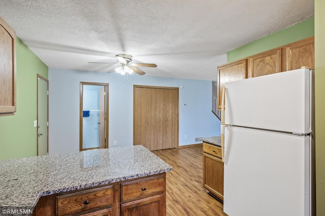 1111 Royal Oaks Dr, Shoreview, MN 55126 - kitchen with freestanding refrigerator, light wood finished floors, ceiling fan, a textured ceiling, and light stone countertops