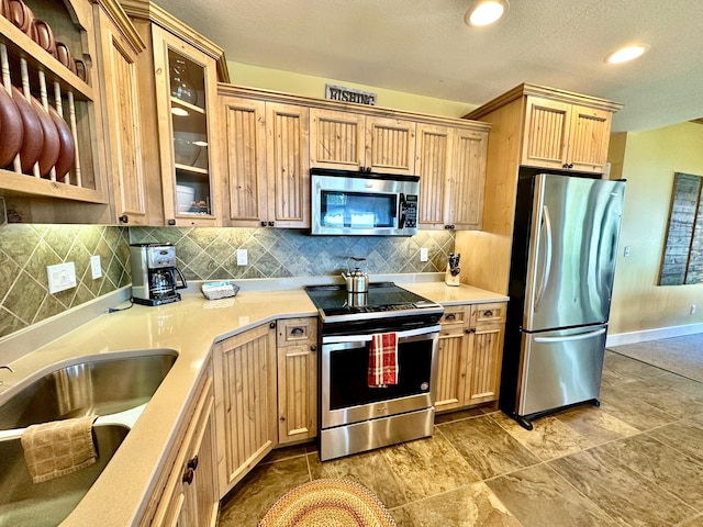 6940 Beach View Ln NW Unit 220-1, Walker, MN 56484 - kitchen with stainless steel appliances, light countertops, light brown cabinets, tasteful backsplash, and glass insert cabinets