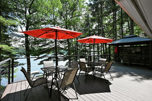 N2590 Warren Rd, Madge Twp, WI 54870 - wooden terrace with outdoor dining area, a gazebo, a water view, and view of wooded area