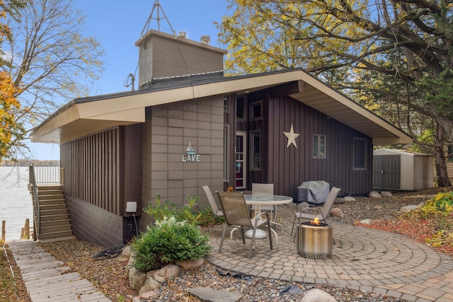 13235 80th St NW, Annandale, MN 55302 - back of property featuring a chimney, a patio area, a fire pit, board and batten siding, and a storage shed