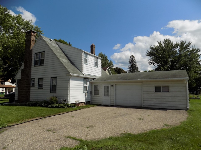 411 Bush St, Lakefield, MN 56150 - back of house featuring a chimney, a garage, roof with shingles, a yard, and asphalt driveway