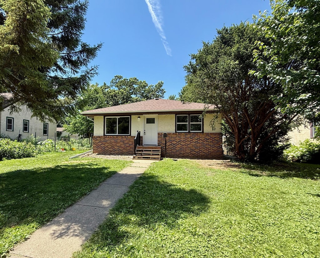 3541 Kyle Ave N, Crystal, MN 55422 - bungalow-style home featuring brick siding, a front lawn, and stucco siding