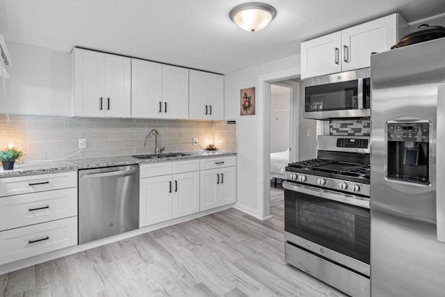 2168 Centerview Ln, Mound, MN 55364 - kitchen featuring stainless steel appliances, tasteful backsplash, white cabinets, light stone counters, and light wood-style flooring