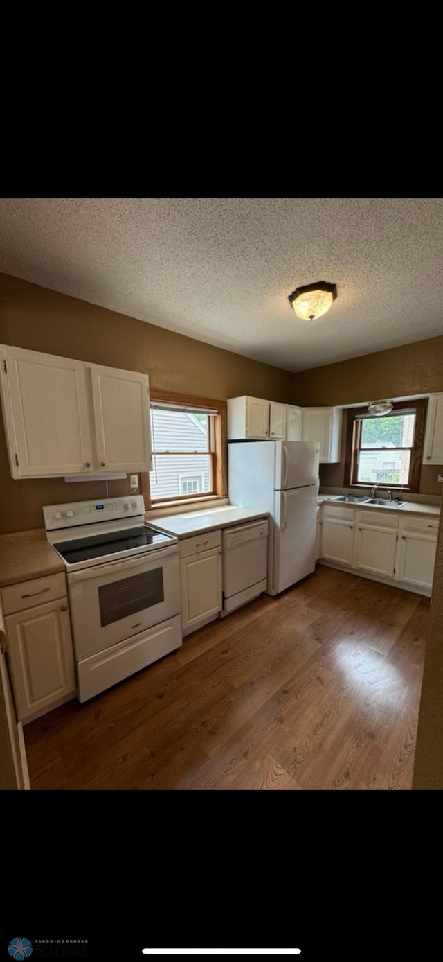 802 11th Ave N, Fargo, ND 58102 - kitchen with white appliances, plenty of natural light, white cabinetry, and a textured ceiling