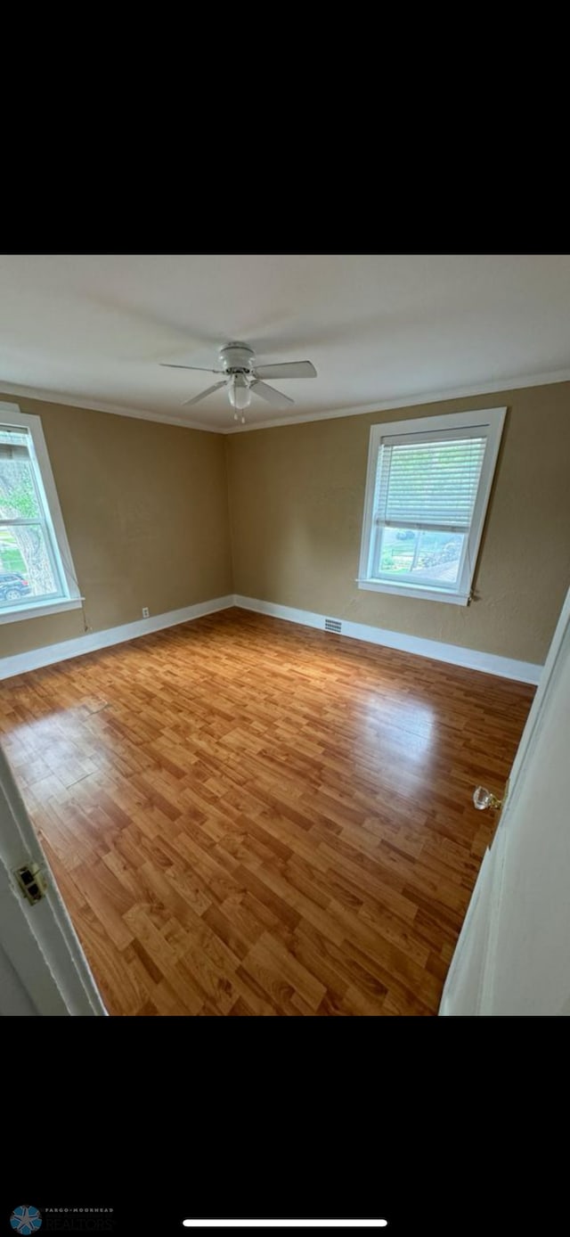 802 11th Ave N, Fargo, ND 58102 - empty room featuring wood finished floors, healthy amount of natural light, ornamental molding, and a ceiling fan
