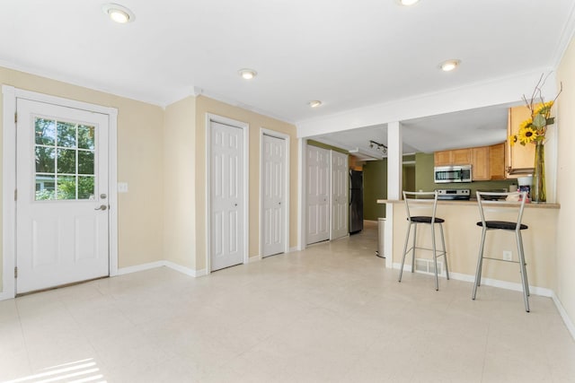 905 Bellows St, West Saint Paul, MN 55118 - kitchen featuring stainless steel microwave, freestanding refrigerator, ornamental molding, a kitchen bar, and a peninsula
