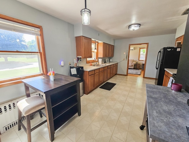 460 3rd St, Bird Island, MN 55310 - kitchen featuring brown cabinetry, freestanding refrigerator, light floors, radiator heating unit, and decorative light fixtures
