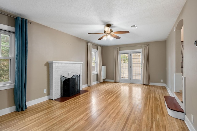 506 6th Ave SW, Austin, MN 55912 - unfurnished living room with light wood-style floors, a ceiling fan, a brick fireplace, and a textured ceiling