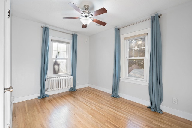 506 6th Ave SW, Austin, MN 55912 - empty room featuring radiator heating unit, ceiling fan, and light wood-style floors