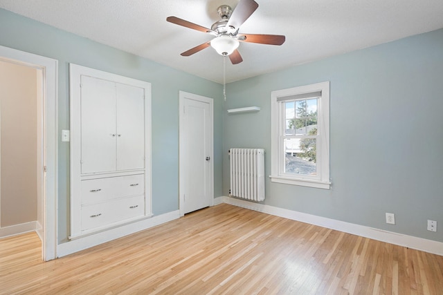 506 6th Ave SW, Austin, MN 55912 - unfurnished bedroom featuring radiator, light wood finished floors, multiple closets, and ceiling fan