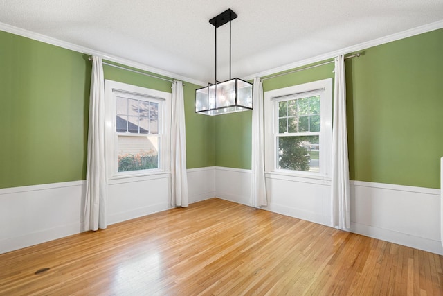 506 6th Ave SW, Austin, MN 55912 - unfurnished dining area with ornamental molding, wood finished floors, a wainscoted wall, and a textured ceiling