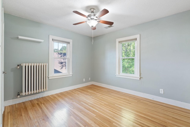 506 6th Ave SW, Austin, MN 55912 - empty room featuring radiator heating unit, a ceiling fan, and wood finished floors