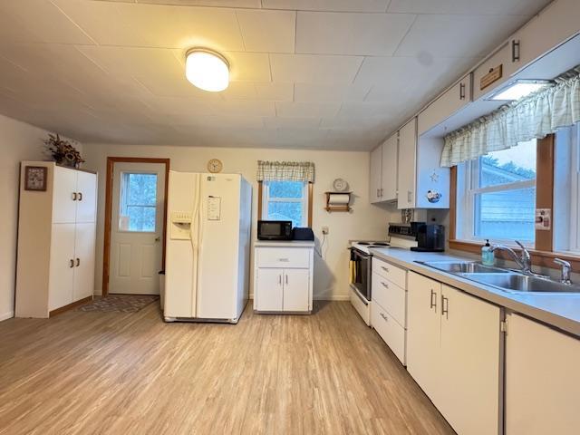 317 2nd St NE, Menahga, MN 56464 - kitchen with white appliances, light wood-style flooring, healthy amount of natural light, and white cabinetry
