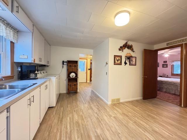 317 2nd St NE, Menahga, MN 56464 - kitchen with light wood finished floors, white cabinetry, and light countertops
