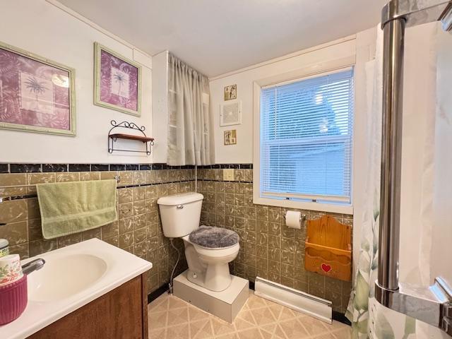 317 2nd St NE, Menahga, MN 56464 - bathroom featuring baseboard heating, vanity, tile walls, and a wainscoted wall